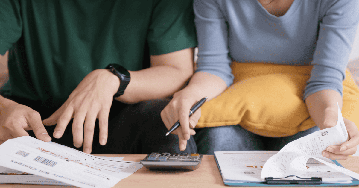 Dos personas controlando gastos y planificando sus investments con facturas y calculadora sobre la mesa.