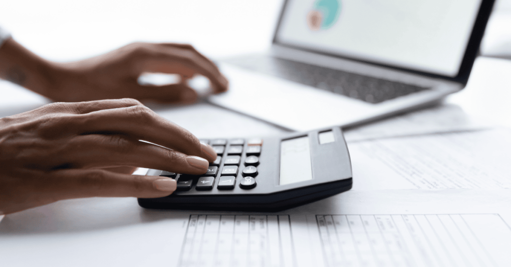 Persona revisando hojas de cálculo y planificando sus investments con ayuda de una calculadora y computadora portátil.