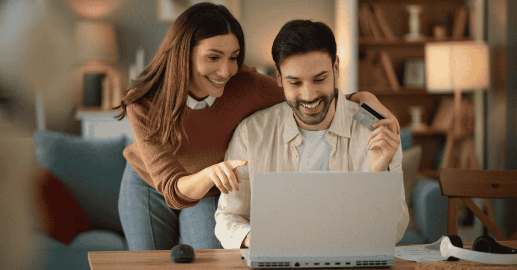 Pareja realizando compras online desde su hogar con tarjeta de crédito, disfrutando de los beneficios del pago digital.