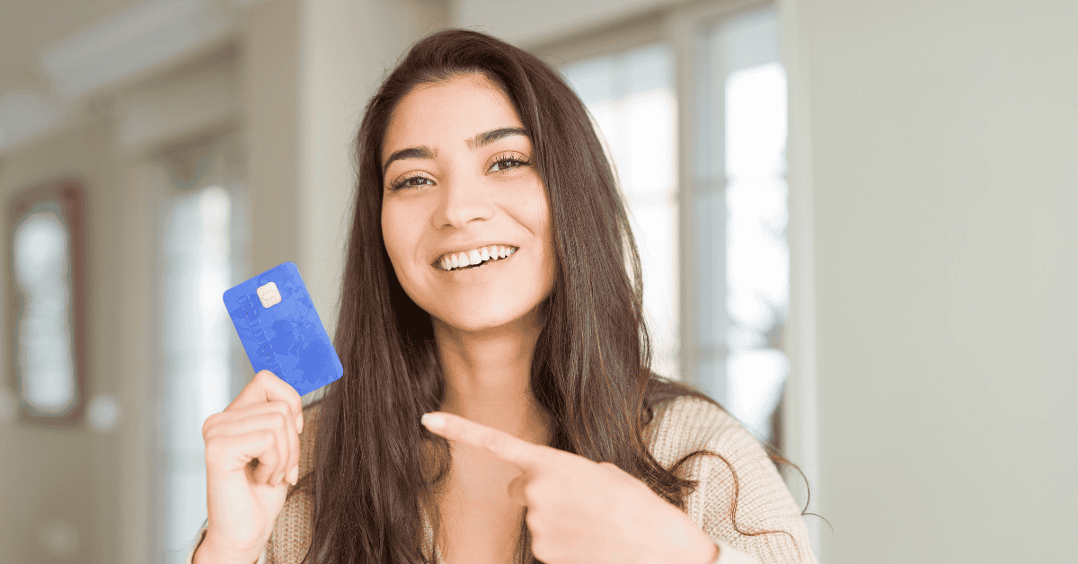 Joven señalando una tarjeta de crédito, representando finanzas digitales y hábitos de inversión.