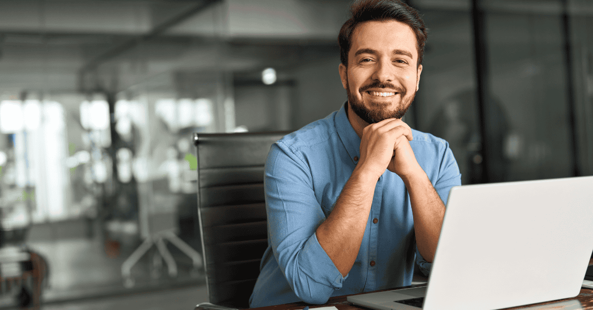 Profesional sonriente trabajando en su laptop, analizando oportunidades de investments y estrategias financieras.