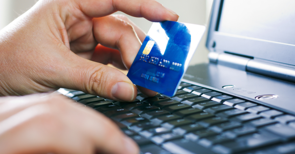 Persona usando una tarjeta de crédito para realizar una compra online, representando pagos digitales seguros.