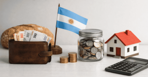 Argentine flag displayed alongside a wallet with peso bills, a jar filled with coins, stacked change, a small house model, and a calculator — symbolizing personal finances and savings in Argentina, including budgeting, housing planning, and money management.